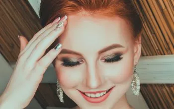 woman wearing bridal gown touching her forehead